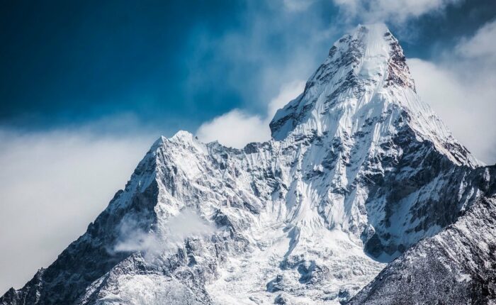 Schneebedeckter Berggipfel mit leichter Wolkenbildung an den Hängen.