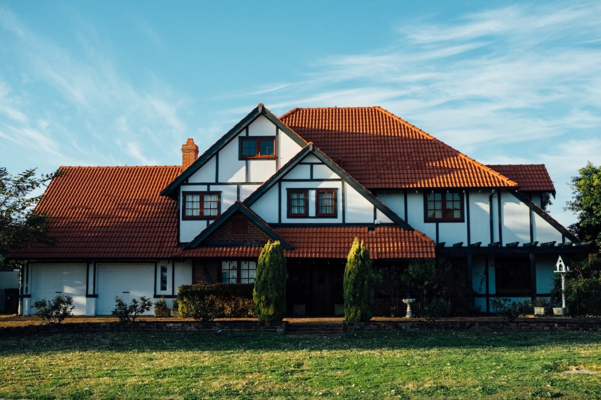Großes Einfamilienhaus mit Garten unter blauem Himmel.